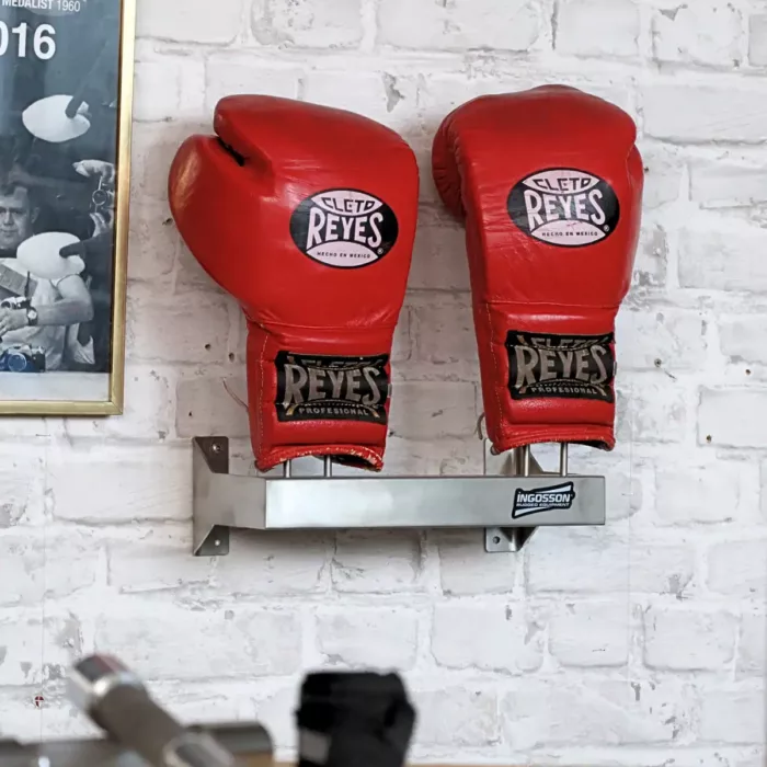 rote CletoReyes Boxhandschuhe auf einem rostfreien Ingosson-Wallrack, das an eine Ziegelwand geschraubt ist