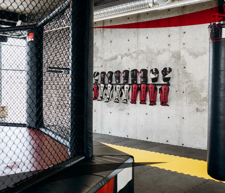 Storage rack for shin guards and boxing gloves bolted to a concrete wall